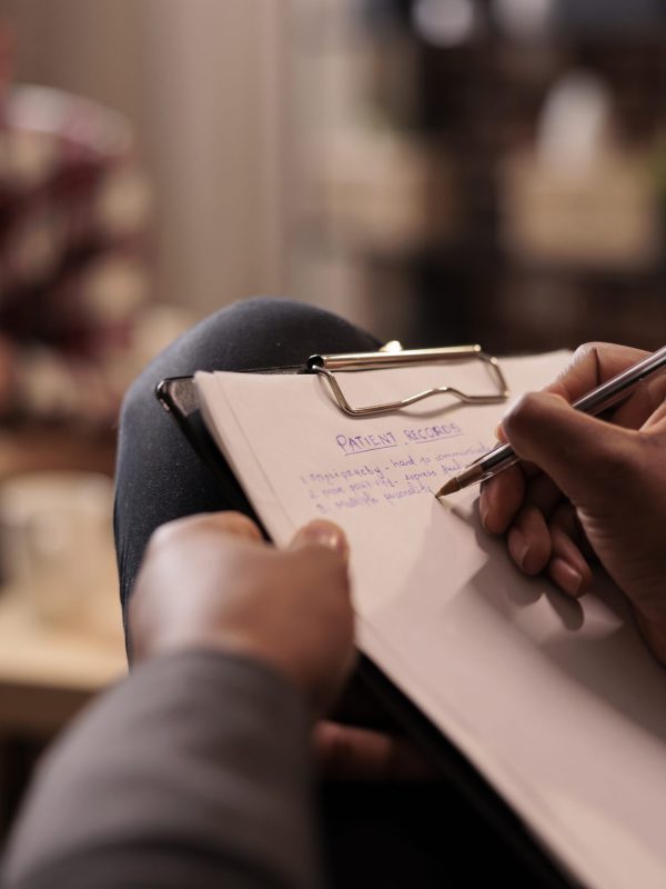 Male psychologist taking notes at couple therapy session to help with relationship issues, counselor giving advice. Explaining marriage problems, using paper to do psychoanalysis. Close up,